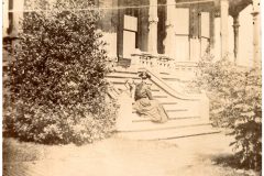 Nellie Flavel and her dog on the front steps of the Flavel House